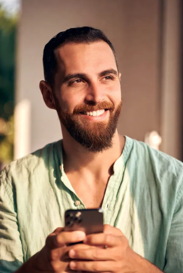 Homme souriant consultant Kano.care sur son téléphone
