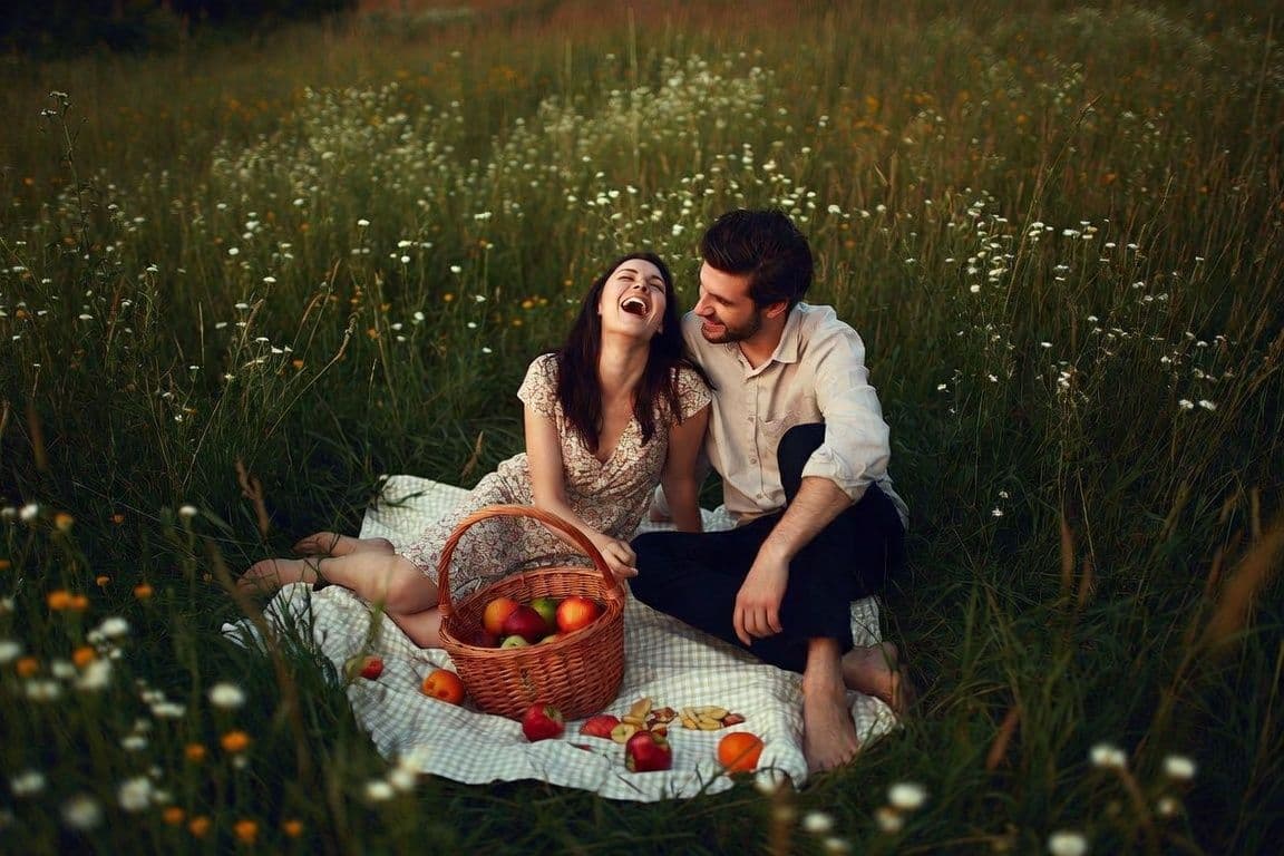 Couple complice pique-niquant dans une prairie Couple complice pique-niquant dans une prairie
